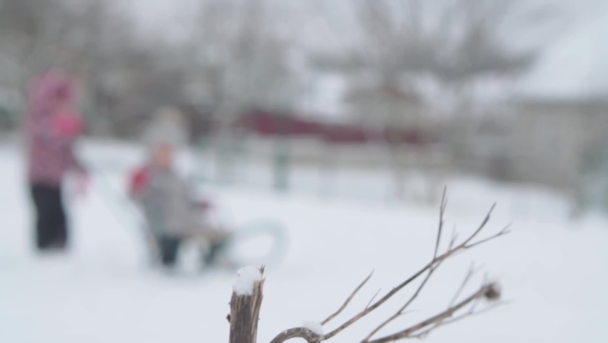 vacation, game, family concept - slo-mo authentic Two happy preschool toddler kids siblings in hats and mittens sledding and rolling each other. snowfall in cold season weather in winter park outdoors