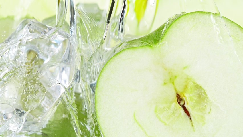 Super Slow Motion Shot of Pouring Water on Apple Slices and Ice Cubes in Glass at 1000 fps.