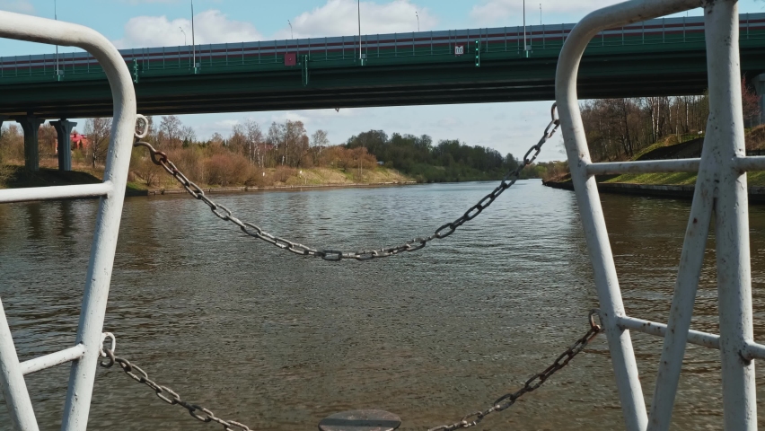 View of river water and its shores from boat approaching a bridge over river. Travelling by ship.
