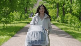Mother with baby stroller on a walk in spring park, mom pushing baby carriage in Alexander Park in the town of Tsarskoye Selo, Pushkin. High quality 4k footage