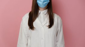 Cropped video of medical woman doctor wear mask to prevent Coronavirus and standing and holding stethoscope, cross arms chest, isolated on pink background. Concept of preventing infectious diseases