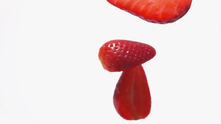 Super close-up of strawberry halves falling diagonally on a white background Royalty-Free Stock Footage #1074079946