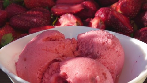Close-up of fresh delicious strawberries falling on the strawberry ice cream
