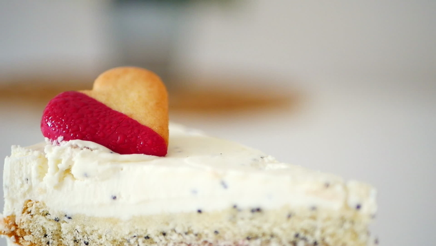 
A piece of delicious cake with different layers, raspberry interlayer, white cream, decorated with a biscuit heart. Valentines day cake