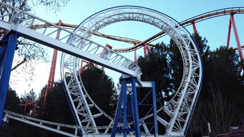 Revolution roller coaster at Six Flags Magic Mountain in California. Static shot of the train travelling through a circular loop with Tatsu roller coaster in the background.