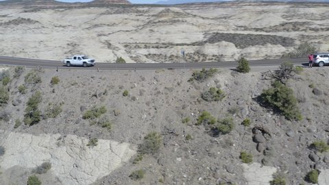 Escalante , Utah , United States - 10 25 2020: Tracking Aerial Shot Follows Convoy of White Trucks and Crossover SUVs as they Drive Along Precarious Mountain Ridge near Escalante Utah