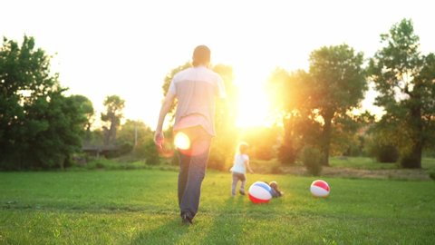 summer, vacation, nature, happy family, childhood, paternity, father Day - Dad with smal preschool children kids run play have fun swinging by hands with big inflatable ball in park at sunset outside