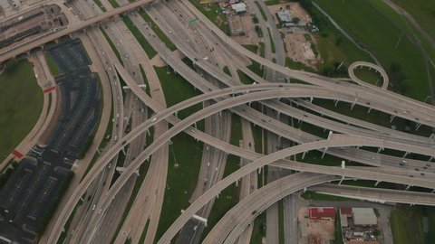 Aerial view of large and complex multilane highway intersection. Cars smoothly driving in lanes through multilevel transport construction. Drone flying forwards and tilt down. Dallas, Texas, US
