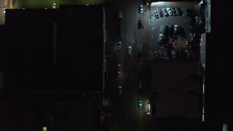 Aerial birds eye overhead top down view of wide multilane downtown streets. Drone following car driving through crossroads. Vertically panning night view of illuminated streets. Dallas, Texas, US