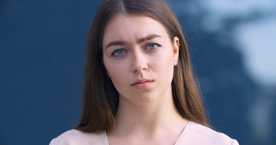 Closeup of female displeased face. Portrait of angry upset bewildered young business woman student standing outdoors at background of city building looking sadly at camera shaking her head disagreeing | Shutterstock HD Video #1074101300