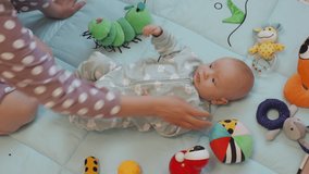 Mother and baby having good time together sitting on floor at home woman playing with her 3 month old baby boy on activity play mat with toys. High quality 4k footage