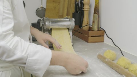 Passing pasta dough through press machine. Closeup, slow motion shot