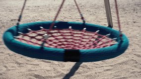 Detail of a swing moving in a playground without people.