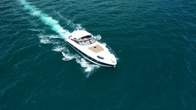 Aerial drone tracking video of small luxury yacht cruising in deep blue open ocean sea
