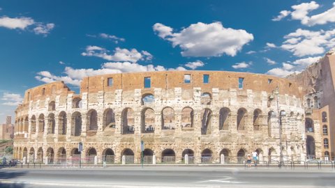 Many tourists visiting The Colosseum or Coliseum timelapse hyperlapse, also known as the Flavian Amphitheatre in Rome, Italy. Traffic on the road. Blue sky with clouds at sunny day