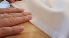 Close-up shot of a woman sticking needles in sheer white cloth. Extreme close up video as hands are working with the needle.