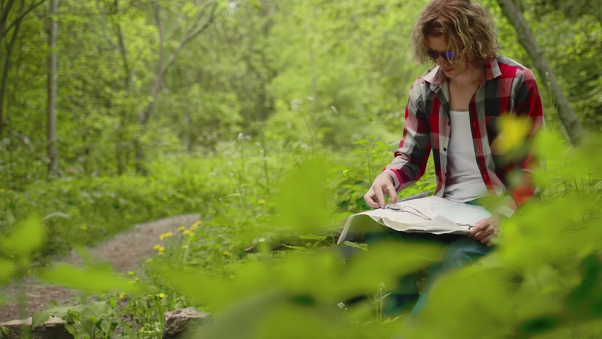 Man sits with compass and map. Orienteering.