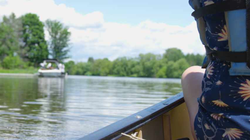 Young woman begins paddling a canoe down a river on a sunny summer day. Close up shot, slow motion.
