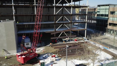 Pittsburgh , Pennsylvania , United States - 02 04 2021: Crane lifting two steel I beams on a construction site. Drone tracking shot.