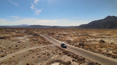 Barstow , California , United States - 01 15 2021: An SUV drives along a dirt road in the Mojave Desert of California.