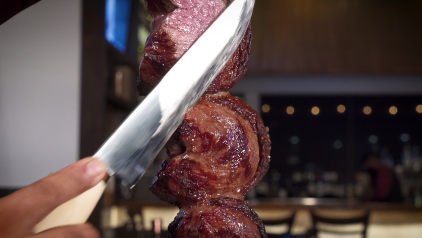 Man slices picanha traditional beef fillet steak at Brazilian steakhouse, HD Royalty-Free Stock Footage #1074158663