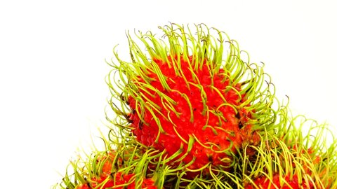 4K  whole red freen color rambutan fruits and one peeled rambutan. Rotating on the turntable isolated on the white background. Close up. Macro