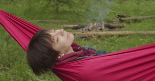 Close up zooming video of woman dreaming in red hammock in wonderful woods slow motion. attractive girl lying sleeping alone in green forest on summer vacation. Relaxation after busy week 