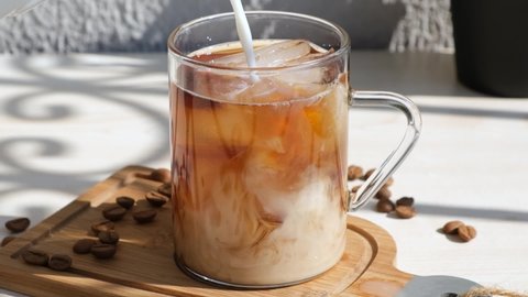 pouring creamy milk into filter brewing iced coffee. pouring milk cream into iced coffee in slow motion.