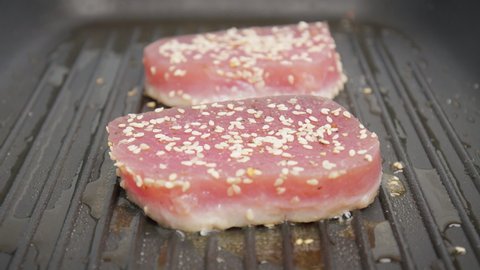 Close-up grilling yellowfin tuna steak on a grilling pan in 4K. Concept frying and cooking tuna steak in slow motion.