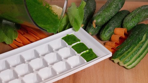 Cooking frozen cubes smoothie with spinach and vegetables on a wooden table