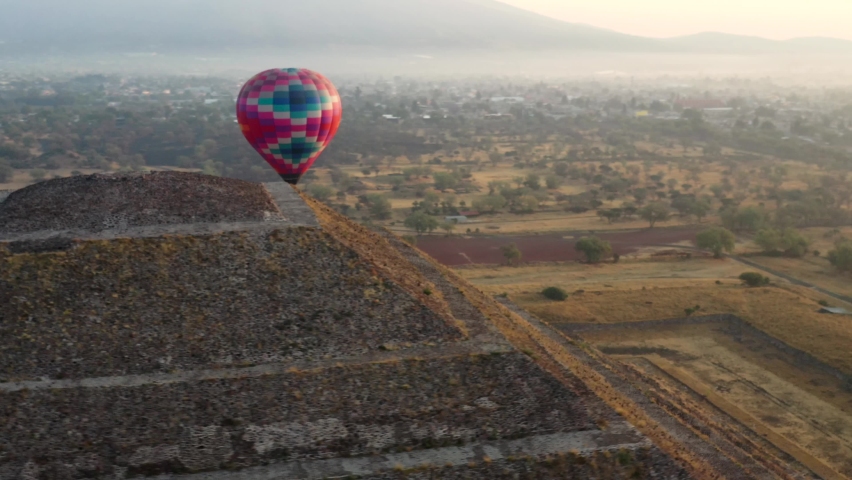 Aerial view of colorful hot air baloon flying over the pyramid of the Aztec culture in Teotihucan Mexico during sunrise, 4K