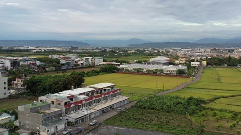 Sliding View Aerial Drone Footage of Urban Agriculture with Grid Farm Land and Rice Paddy Field and Beautiful Blue Sky and Mountains at the background at Doliu City Taiwan.