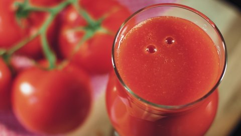 Close-up shooting. Tomato juice is poured into a crystal glass. Next to it is a sprig of tomatoes.