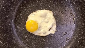 Chicken egg in a frying pan, top view. Cooking a fried egg. Mobile phone video.