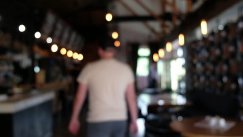 Blurred pub background. A visitor passes in the background to make an order at the bar and leaves.