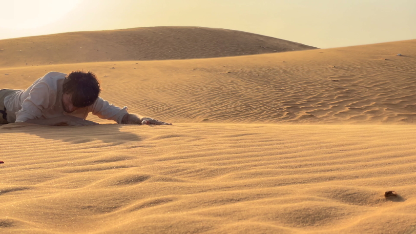 A man in an office cloth crawls up a dune in a desert. Overcoming challenges in business