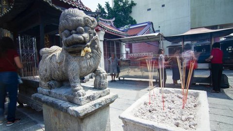 Georgetown , Penang , Malaysia - 07 20 2019: Timelapse people burn joss stick and pray in front of statue lion