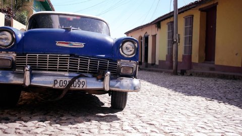 Trinidad , Cuba - 03 08 2021: Vintage cars driving along the cobblestone roads of Trinidad Cuba