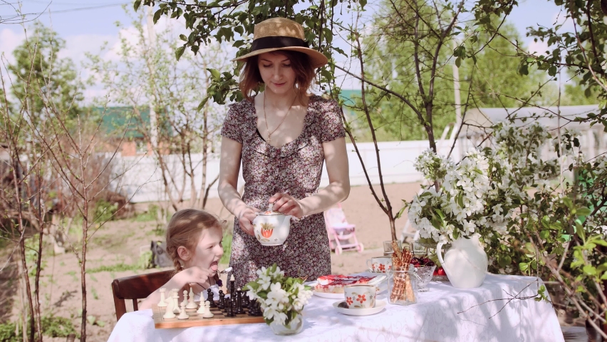Mom and daughter have breakfast outdoors in the apple orchard in the spring. Happy family concept
