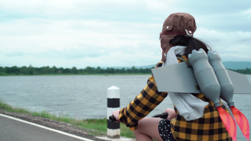 Asian kid with jet pack riding bike. Child girl playing at outdoor