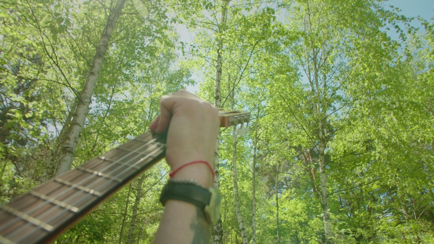 Happy handsome mature gray haired male camper with acoustic guitar and attractive female backpacker sitting on travel chairs near campfire, enjoying recreation and nature on adventure trek.