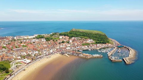 Aerial drone footage of the beach front in the town of Scarborough in North Yorkshire, England UK showing the beach front and boating harbour on a sunny summers day