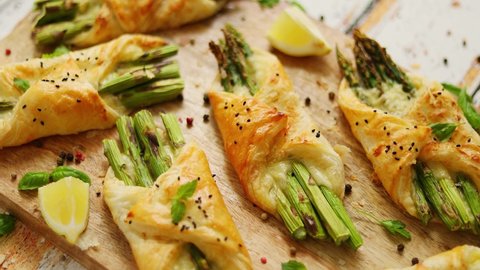 Baked green asparagus wrapped in puff pastry. Served on wooden board. With selective focus