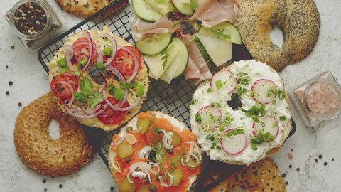 Delicious Bagel sandwiches with creamy cheese, ham, hummus, salmon and vegetables