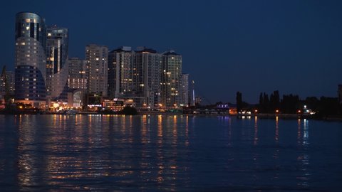 Krasnodar, Krasnodar Territory, Russia, June 9, 2021: High-rise buildings stand against the background of the night river. The city lights are reflected in the water. Night city landscape