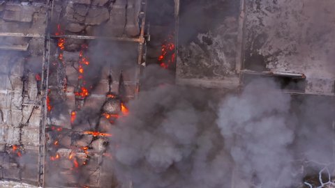 Aerial view rising above smoke and flames, in collapsed building, bomb aftermath - top down, drone shot