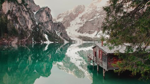 Prags , South Tyrol , Italy - 05 14 2021: Wooden hut by a beautiful mountain lake in the Dolomites. Lago di braies - Pragser Wildsee South Tyrol.