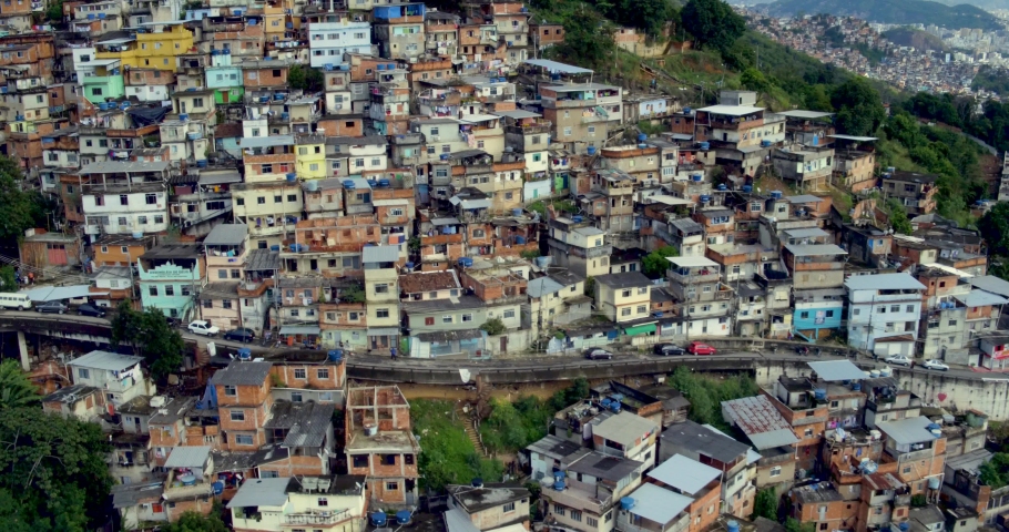 Aerial establishing shot of the Hill of Pleasures slum in Rio de Janeiro. Slow flyover, rise up to reveal the city. Royalty-Free Stock Footage #1074238220