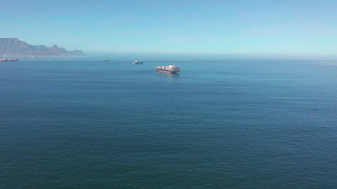 A large container ship for transporting goods near the port of Capetown, South Africa. A container ship carries cargo across the ocean. Transportation. Delivery. Logistics. Aerial 4K shot.
