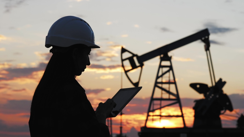 Industrial, oil and gas concept. Silhouette working engineer oil rig. Oil rigs at sunset. Silhouette of woman engineer with tablet overseeing the site of crude oil production at sunset. | Shutterstock HD Video #1074243905